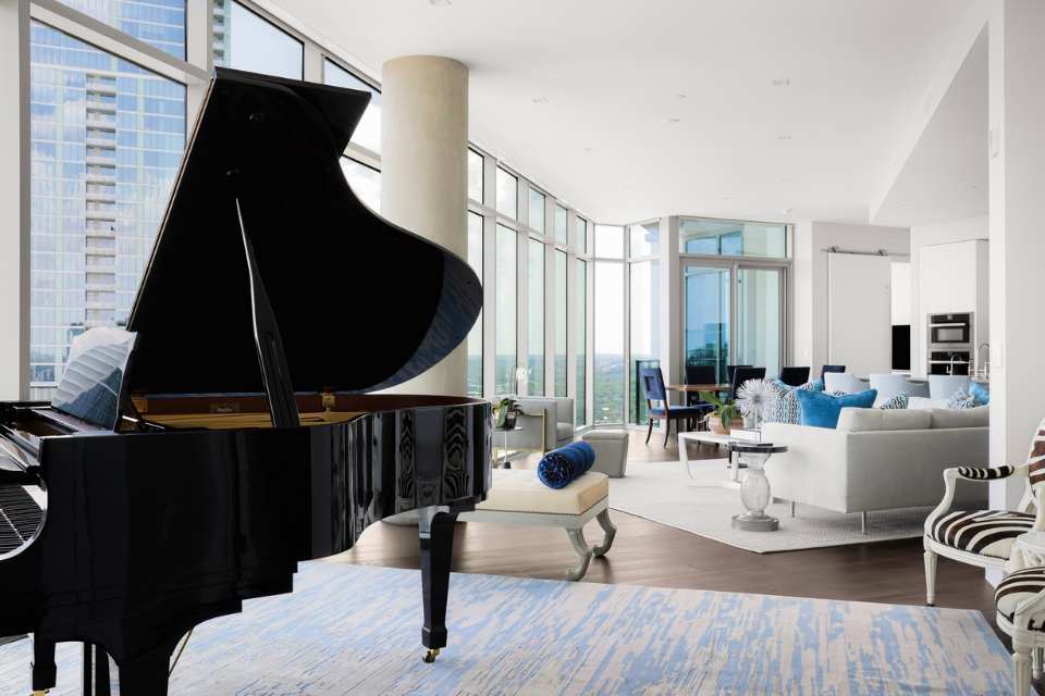 grand piano in open concept living room with blue and white silk custom rug underneath